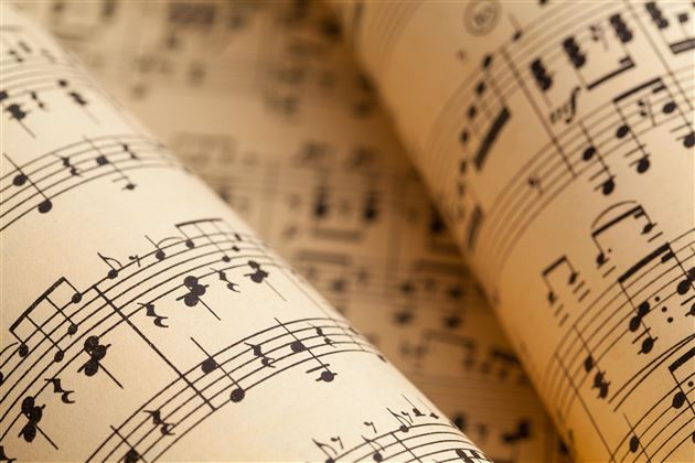 Deux rouleaux de partitions musicales avec des notations sur un fond clair. Ils montrent de la musique classique et sont disposés de manière artistique.