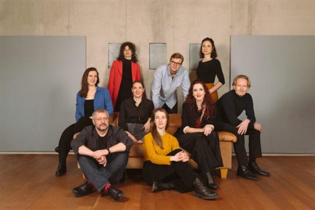 Un groupe de dix personnes dans un intérieur moderne. Ils sont assis et debout dans différentes poses et styles vestimentaires.