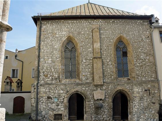 Een historisch gebouw van steen met gotische ramen. De façade toont interessante architectuur en bevindt zich in een rustige omgeving.