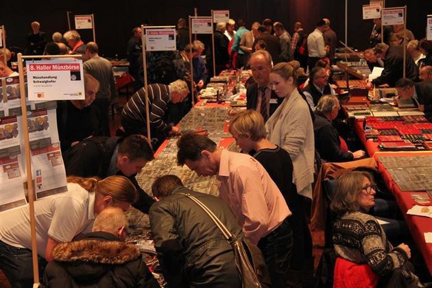 Una fiera affollata con molti stand e visitatori che osservano modelli e pezzi da collezione. L'atmosfera è conviviale e vivace.