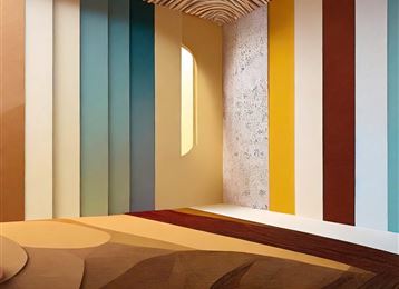 A modern room with colorful walls in various shades. Soft light falls onto the floor through a window.