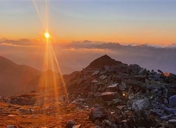Ein atemberaubender Sonnenaufgang über den Bergen. Steiniger Untergrund und weiche Wolken verleihen der Landschaft eine mystische Atmosphäre.