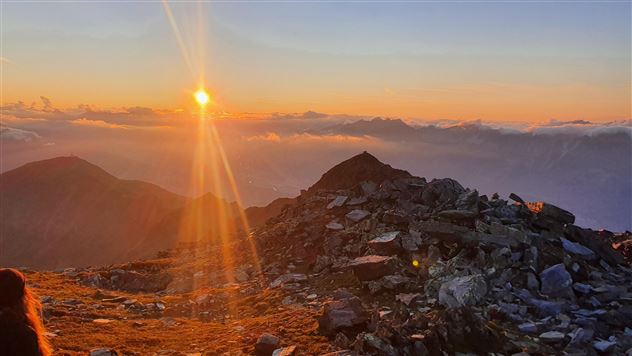 Ein atemberaubender Sonnenaufgang über den Bergen. Steiniger Untergrund und weiche Wolken verleihen der Landschaft eine mystische Atmosphäre.