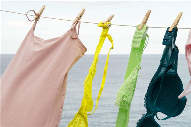 A black mannequin with a red hat is standing in front of a white wardrobe. The hat has a shiny surface and attracts attention.