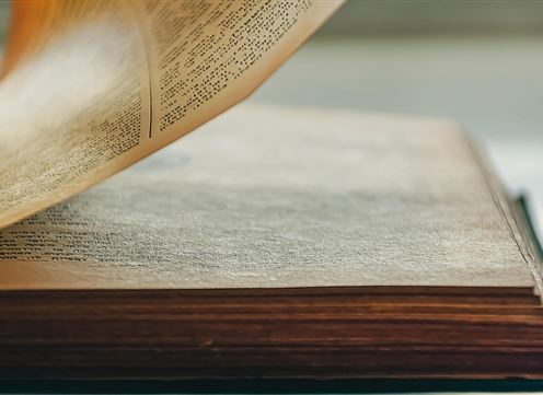 An open book with yellowed pages. The pages display printed text and a clear, calm texture.