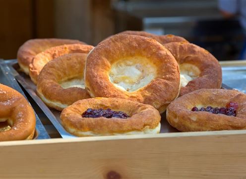 A selection of fresh, round pastries on a tray. Some are filled with jam, while others are plain and golden brown.