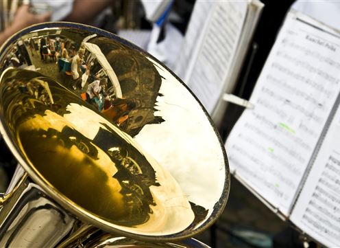 Una tuba lucente con immagini riflettenti di persone. Sullo sfondo si possono vedere fogli di musica.