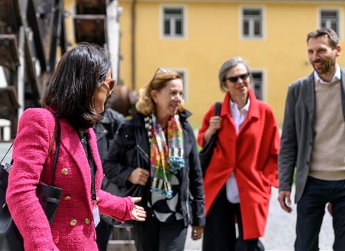 Een groep van vier mensen staat in de open lucht. Ze lachen en lijken te praten.