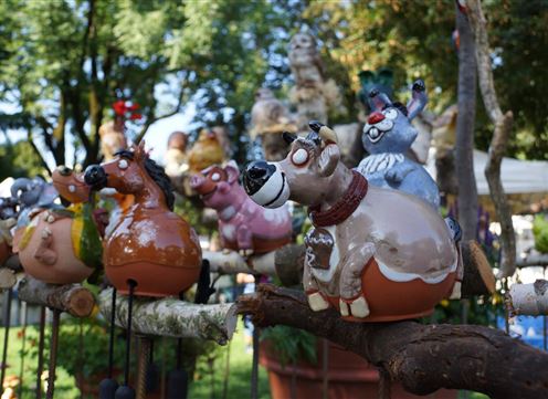 Bunte Tontiere sitzen auf einem Ast, umgeben von grünen Bäumen. Die Figuren haben verschiedene Designs und verleihen der Szene einen fröhlichen Eindruck.
