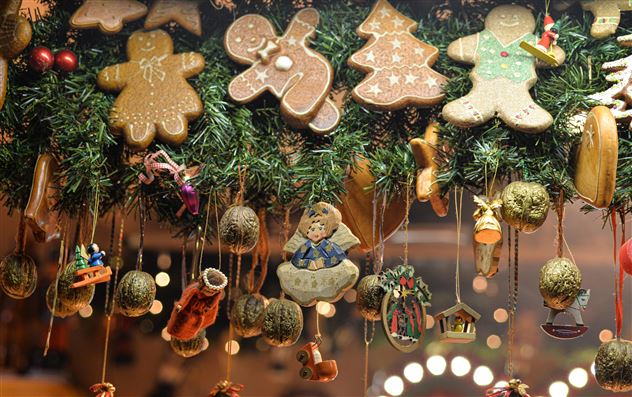 Ein festlich dekoriertes Weihnachtsfenster mit Lebkuchenfiguren und traditionellen Ornamenten. Die bunten Weihnachtsanhänger und der grüne Kranz schaffen eine gemütliche Stimmung.