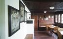Een gezellige eetkamer met houten wandbekleding en een grote eettafel. Aan de muur hangen verschillende foto's en decoraties.