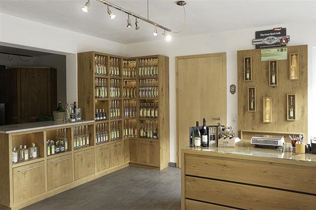 An inviting sales area with wooden shelves displaying various bottles. On the counter, there are additional products and information.