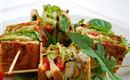 A delicious sandwich platter with fresh vegetables and salad. The sandwiches are beautifully arranged and secured with toothpicks.