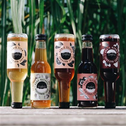 Cinq bouteilles de boissons rafraîchissantes sont posées sur une table. Les boissons ont différentes couleurs et sont dotées d'étiquettes accrocheuses.