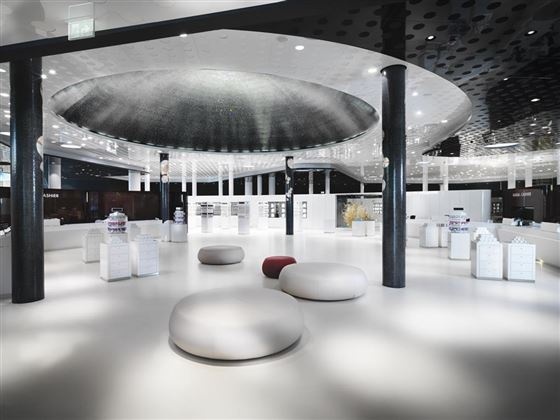 Un negozio moderno ed elegante con un grande elemento a cupola nel soffitto. Sedute rotonde e un arredo luminoso e minimalista creano un'atmosfera accogliente.