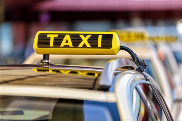 Un taxi avec un panneau jaune sur le toit. Le panneau indique le mot "TAXI" en grandes lettres.