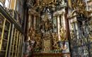 A magnificent altar with golden sculptures and intricate decorations. The colorful walls and windows give the room an impressive atmosphere.