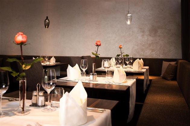 Un restaurant élégant avec des tables dressées. Sur chaque table se trouve une rose et l'atmosphère est conviviale.