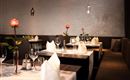 Un restaurant élégant avec des tables dressées. Sur chaque table se trouve une rose et l'atmosphère est conviviale.