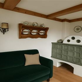 Une salle de séjour confortable avec un canapé vert et un four traditionnel. Des miroirs décoratifs et une lampe sont accrochés au mur.