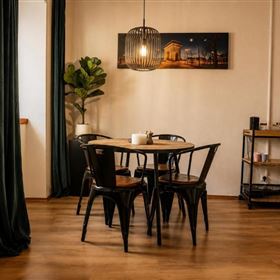 Un coin repas accueillant avec une table ronde et des chaises élégantes. Un tableau est accroché au mur et une plante verte apporte de la fraîcheur.