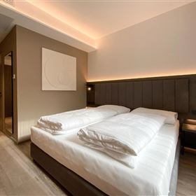 A modern room with two beds and minimalist design. The soft lighting creates an inviting atmosphere.