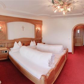 Une chambre d'hôtel confortable avec deux lits et des meubles en bois rustiques. La pièce a un tapis rouge et une atmosphère accueillante.