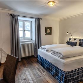 A cozy bedroom with a large double bed and modern furniture. The room has a window that lets in natural light.