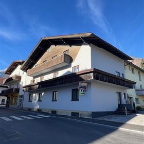 Un moderno edificio a due piani con un tetto angolato. Il cielo è sereno e blu, e la strada davanti alla casa è ben asfaltata.