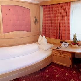 Une chambre confortable avec un lit rond et un coin salon douillet. La fenêtre laisse entrer beaucoup de lumière naturelle et la décoration est accueillante et chaleureuse.