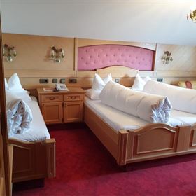 Une chambre confortable avec plusieurs lits et un revêtement en bois. L'aménagement est traditionnel et les murs sont peints en clair.