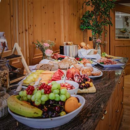 Un ricco buffet per la colazione con frutta fresca, pane e affettati. L'atmosfera è accogliente e confortevole.