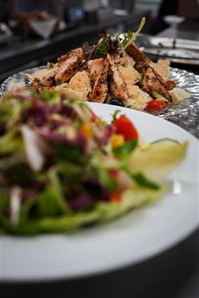Un delizioso piatto con pollo alla griglia su un letto di verdure e insalata. In primo piano si vede un'insalata fresca con verdure colorate.