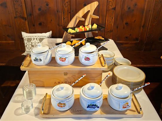 A beautifully decorated buffet with various teapots and snacks. In the background are plates and more delicacies.