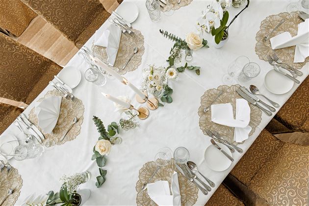 Un tavolo elegante apparecchiato con decorazioni di classe. Ci sono tovaglioli bianchi, posate e composizioni floreali.