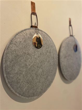 Two round, gray felt panels hang on the wall. Each panel has a hanging tag with a motif.