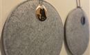 Two round, gray felt panels hang on the wall. Each panel has a hanging tag with a motif.