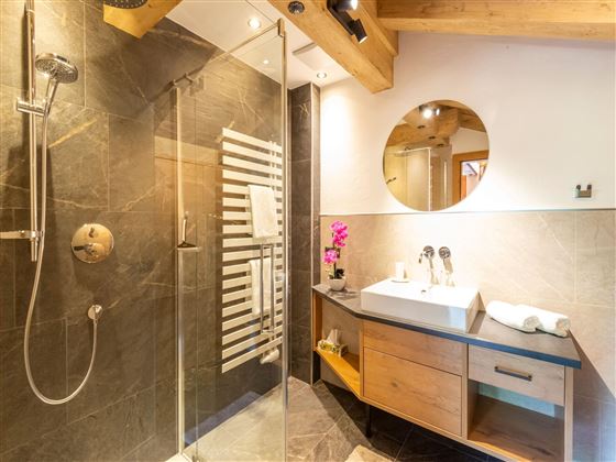 A modern bathroom with a glass shower and an elegant sink. The wooden details and stylish lighting create an inviting atmosphere.