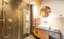 A modern bathroom with a glass shower and an elegant sink. The wooden details and stylish lighting create an inviting atmosphere.