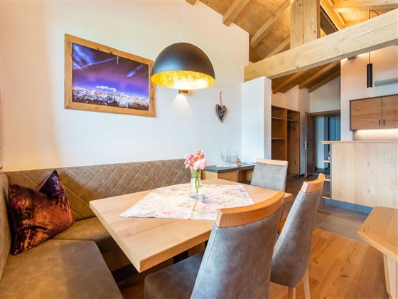 A modern dining room with a wooden table and elegant chairs. The warm colors and good lighting create an inviting atmosphere.