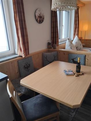 Een gezellige eetruimte met een houtkleurige tafel en stijlvolle stoelen. De ramen laten veel licht binnen en de ruimte is modern ingericht.