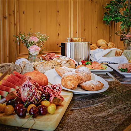 Un ricco buffet per colazione con diversi panini, frutta e affettati. La presentazione accattivante invita a gustare.