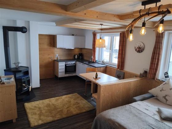 Een gezellige woning met lichte houten meubels en een open woonruimte. De keuken is modern en goed uitgerust, en een zacht tapijt ligt op de vloer.