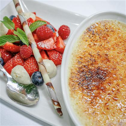 Un delizioso dessert a base di crème brûlée e frutti di bosco freschi. I piatti sono elegantemente disposti e appaiono invitanti.