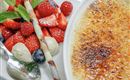 Un delizioso dessert a base di crème brûlée e frutti di bosco freschi. I piatti sono elegantemente disposti e appaiono invitanti.