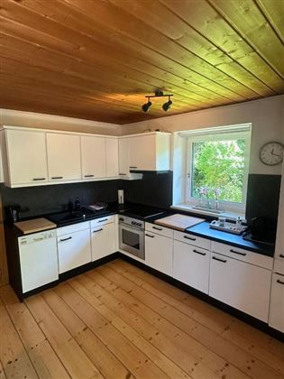 Una cucina moderna con armadietti bianchi e piano di lavoro nero. Una grande finestra offre molta luce naturale.