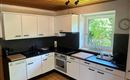 Una cucina moderna con armadietti bianchi e piano di lavoro nero. Una grande finestra offre molta luce naturale.