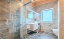 A modern bathroom with a large shower and elegant wood details. The sanitary facilities are clearly structured and offer plenty of natural light.