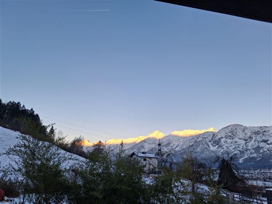 Een mooi uitzicht op besneeuwde bergen in de vroege ochtend. De lucht is helder en de toppen zijn verlicht door zonlicht.