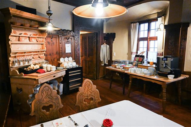 A cozy room with rustic furniture. On a table, there are various foods and drinks for a breakfast buffet.